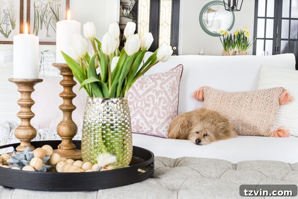 Spring Refresh Living Room Reveal 5 Close-up of a decorative tray on an ottoman with flowers and candles, offering 'spring decor ideas' for a 'cozy living room'.