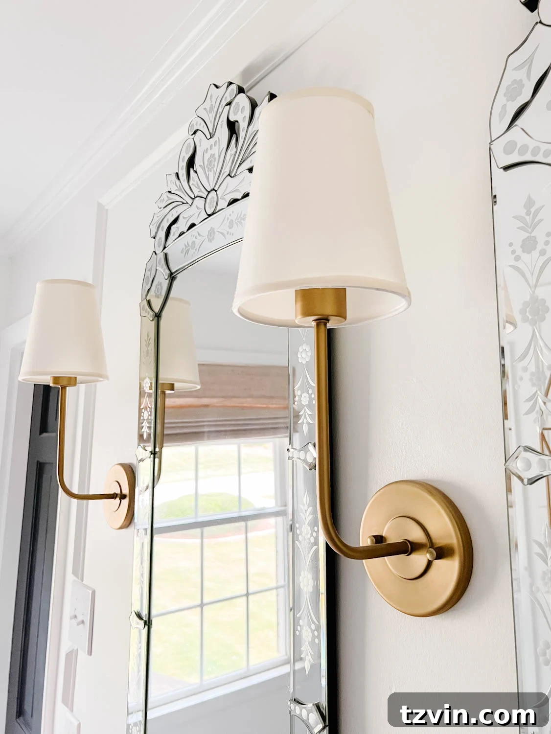 Elegant vintage wall sconces flanking ornate Venetian mirrors in a luxurious bathroom setting.