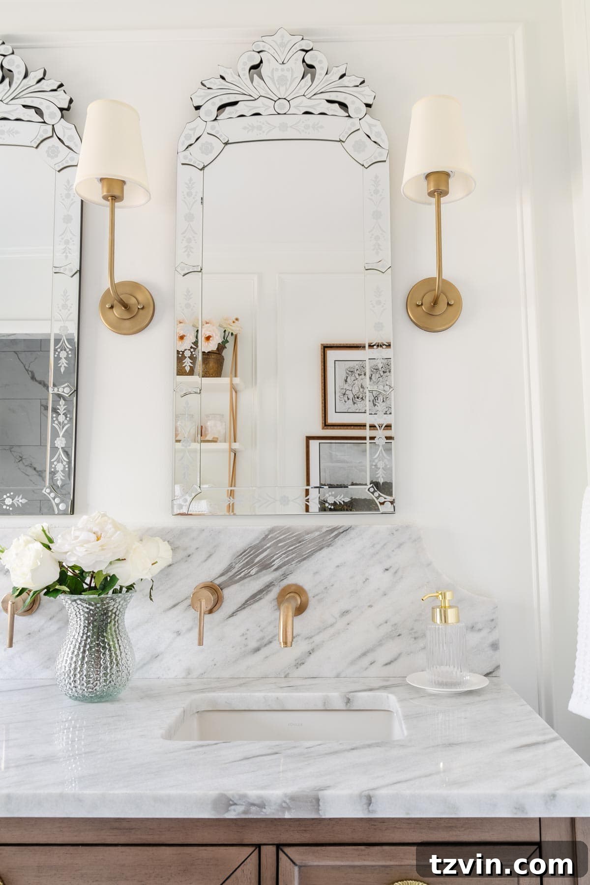 Elegant shaded vintage wall sconces flanking a decorative Venetian mirror in a luxurious bathroom with a marble countertop.