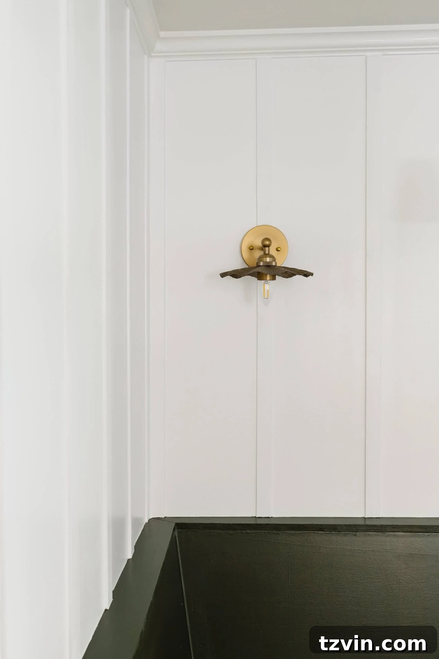 Delicate ruffled flower vintage brass wall lights mounted on a board and batten wall in a sunlit breakfast nook.