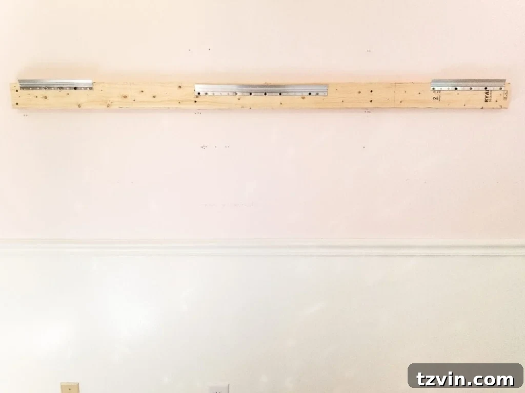 Crafting a Ballet Barre and Mastering Chair Rail Decor 5 Close-up of Hangman hangers screwed into the upper 2x4 board for mirror attachment. Secure mirror hanging method for a DIY ballet barre. #MirrorInstallation #DIYTips #HomeImprovement #SafeHanging