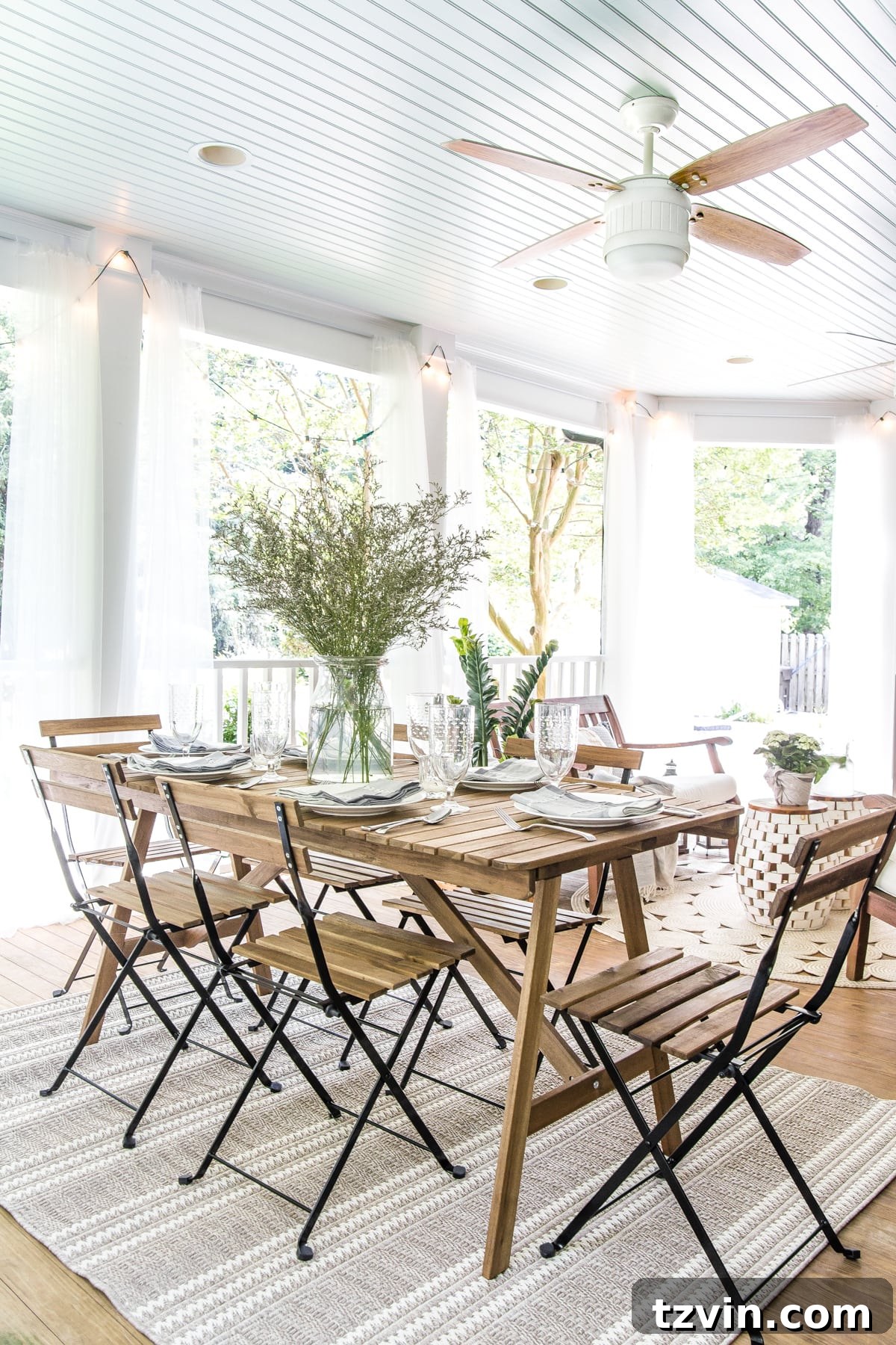 The outdoor dining table set on the back porch, featuring the haint blue ceiling and a ceiling fan for comfort.