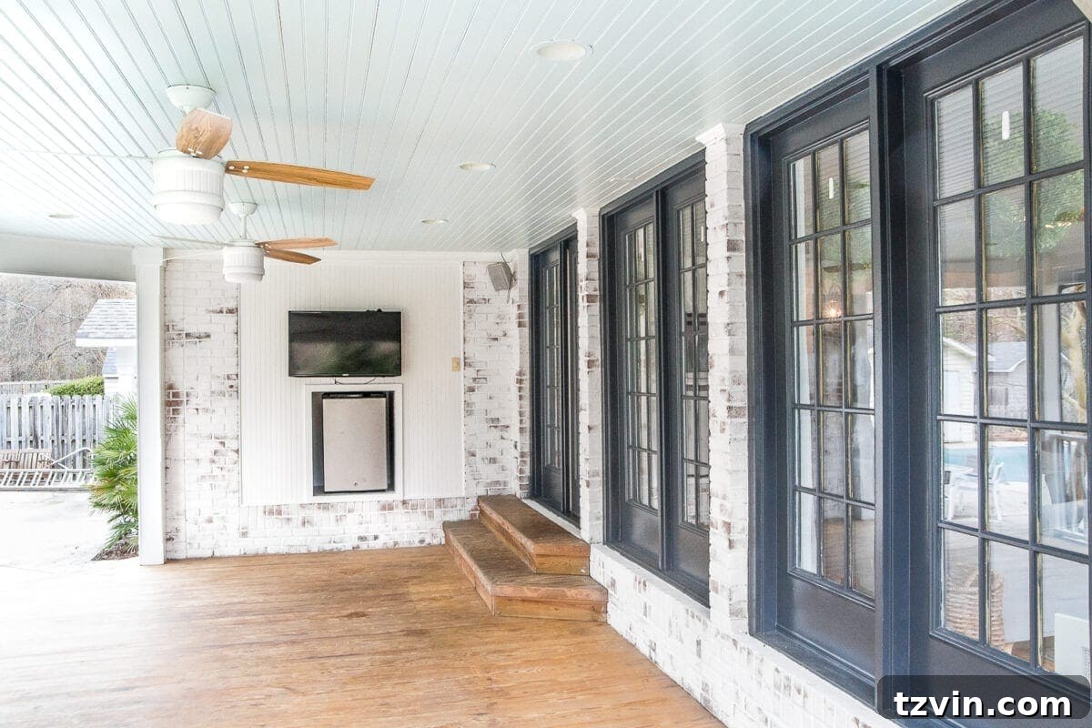 The back porch featuring newly limewashed brick, a haint blue ceiling, and dramatic black doors, creating a striking exterior.