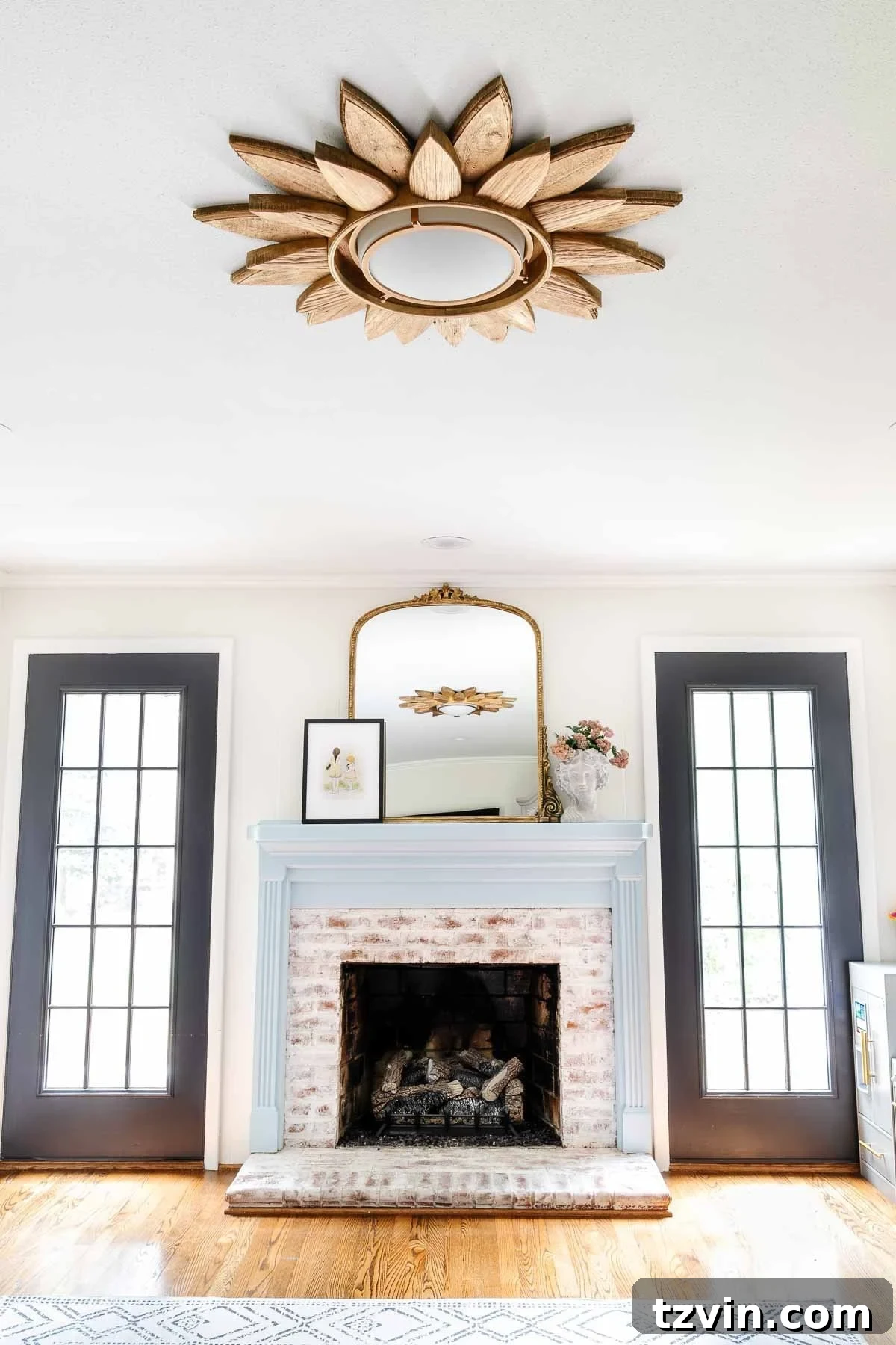 23 Smart Hacks to Make Your Small Room Feel Instantly Bigger 18 white playroom with black French doors and light blue mantel styled with a mirror and bust planter and sunburst light fixture