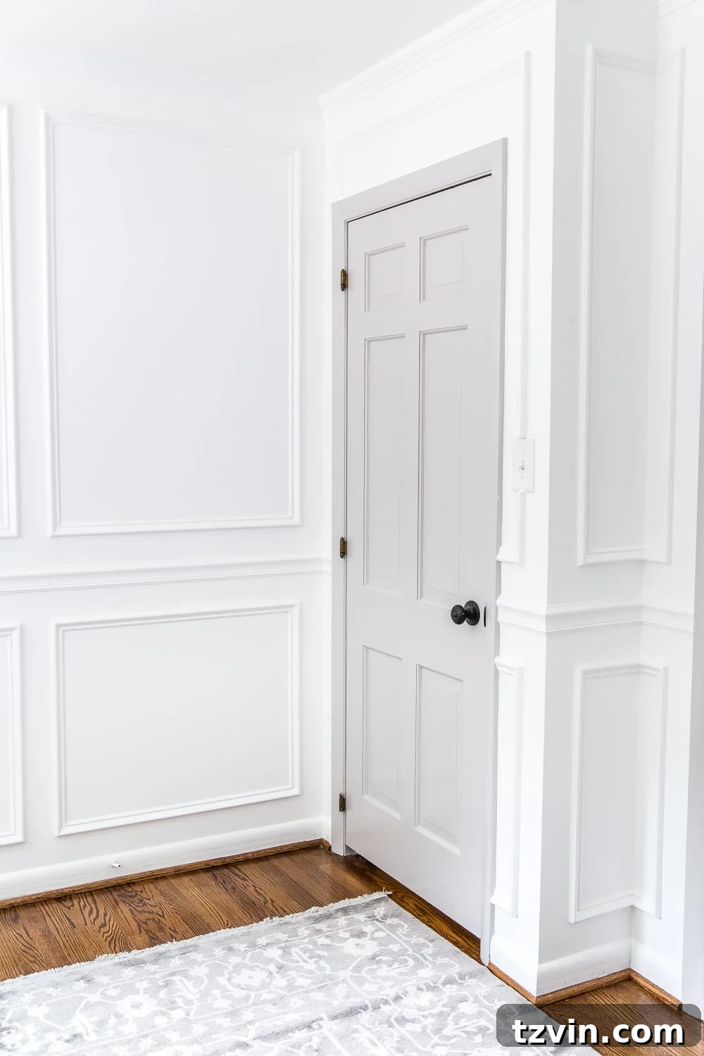 gray painted door with white walls and picture frame molding in a nursery