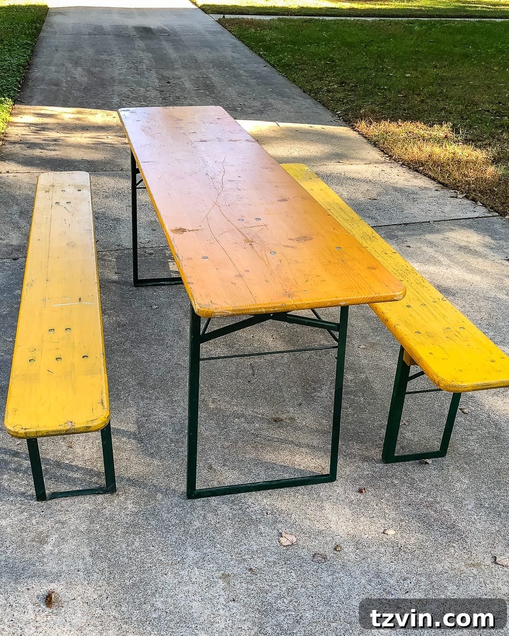 German beer garden table before makeover, showing yellowed wood and peeling green paint on metal legs.