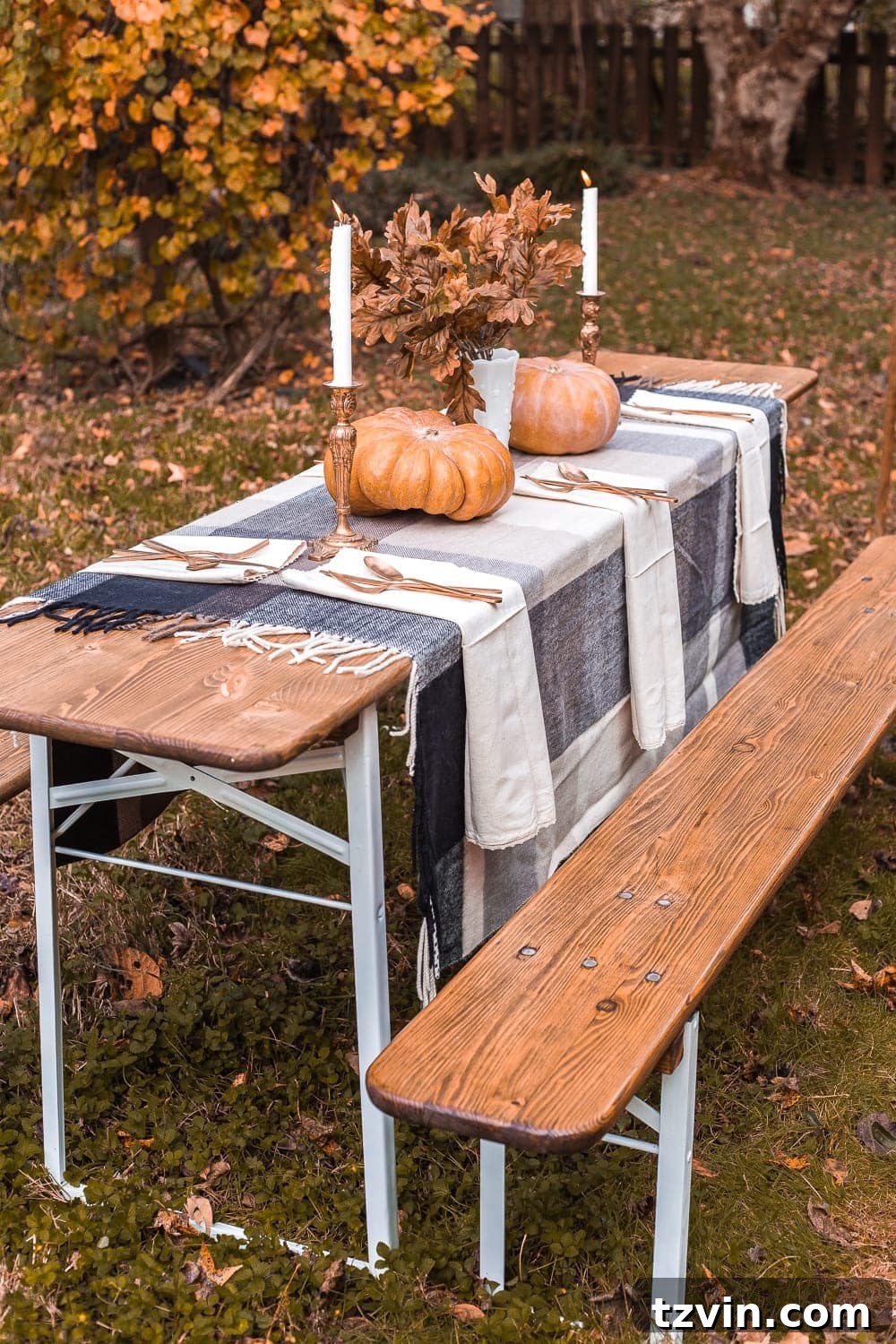 Beautifully decorated antique beer garden table set up for an alfresco Thanksgiving dinner with string lights and fall decor.
