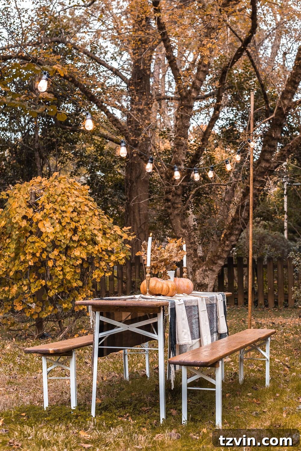 Alfresco fall beer garden table at dusk, showcasing the warm glow of string lights and autumn decorations.
