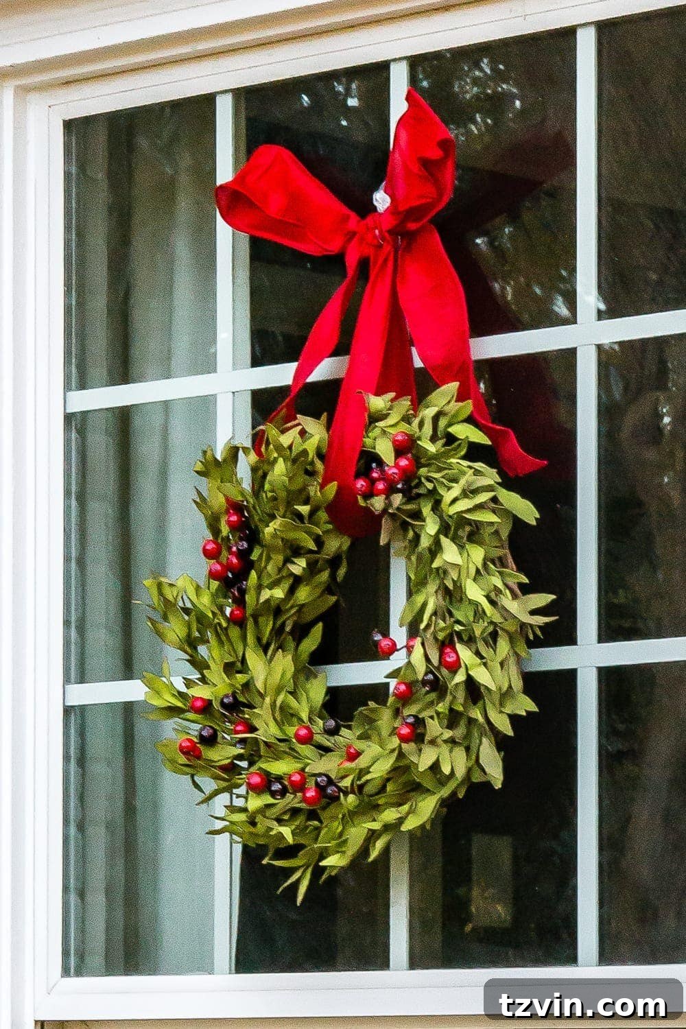 Colonial Charm Outdoor Christmas Wreaths 8 A window adorned with a lush holly and boxwood Christmas wreath, looking incredibly lifelike.