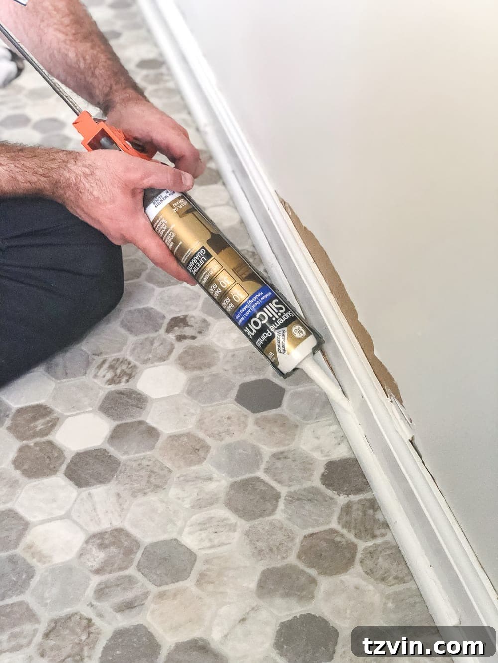 Install Sheet Vinyl Flooring Over Tile The Easy DIY Way 17 Applying white silicone caulk to newly installed molding