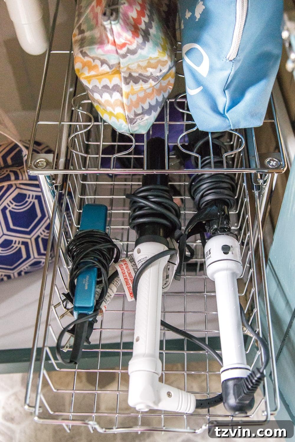 Bottom vanity cabinet with stackable wire baskets, holding hair styling tools like a dryer, curling iron, and straightener. #HairToolStorage #UnderSinkOrganization #FunctionalBathroom