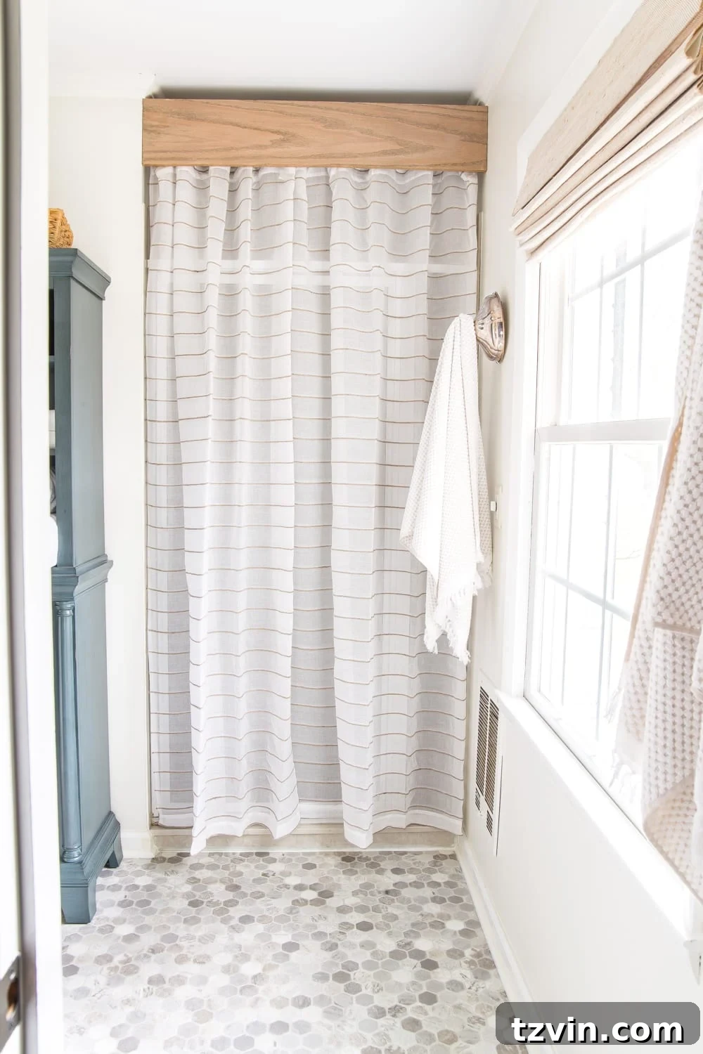 Master Bathroom Makeover: Stunning Results On A Budget 12 Refreshed shower area with semi-sheer curtain covering old door and DIY wooden cornice