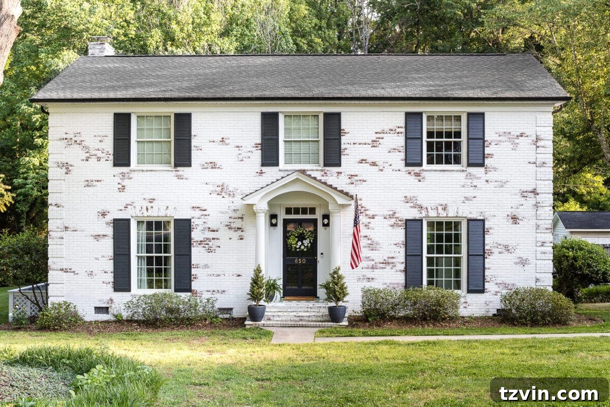 Two Years In: Our Home's Stunning Before and After 4 After shot of a limewashed brick colonial home, featuring updated landscaping and modern farmhouse exterior details.