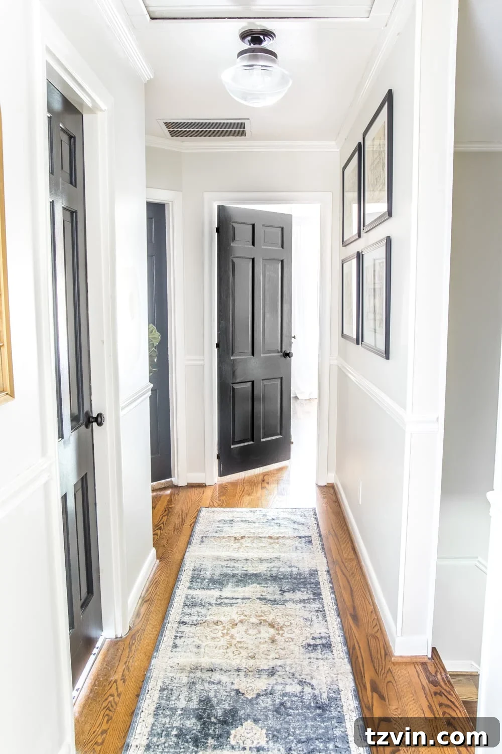 light gray painted hallway with dark charcoal doors, a runner, new lighting, and wall decor
