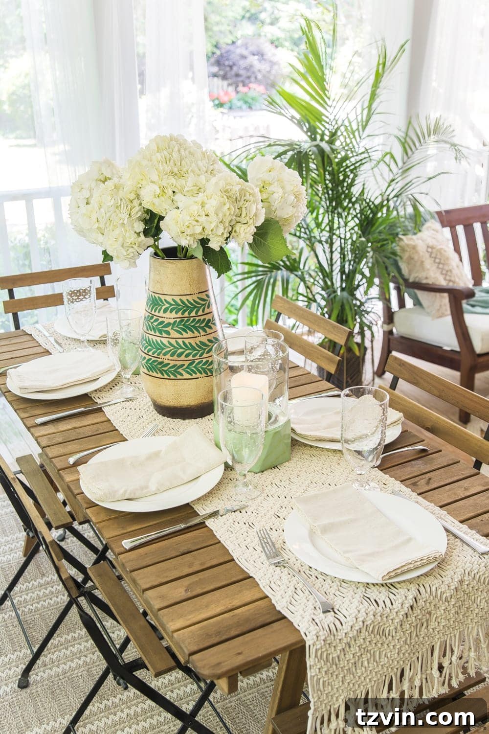 Glass votive lanterns on an outdoor table with string lights in the background, creating evening ambience on a tropical boho back porch.