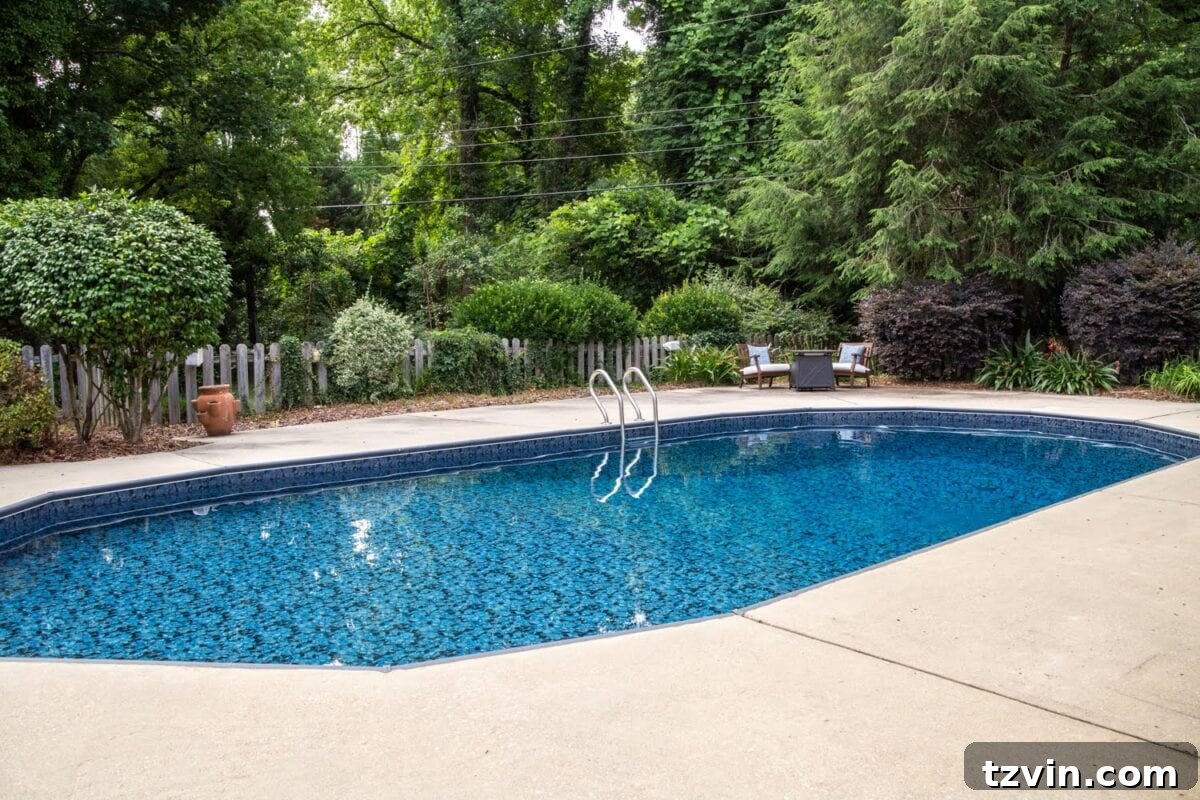 Wide view of the renovated backyard featuring the Obsidian pool liner and lush surroundings