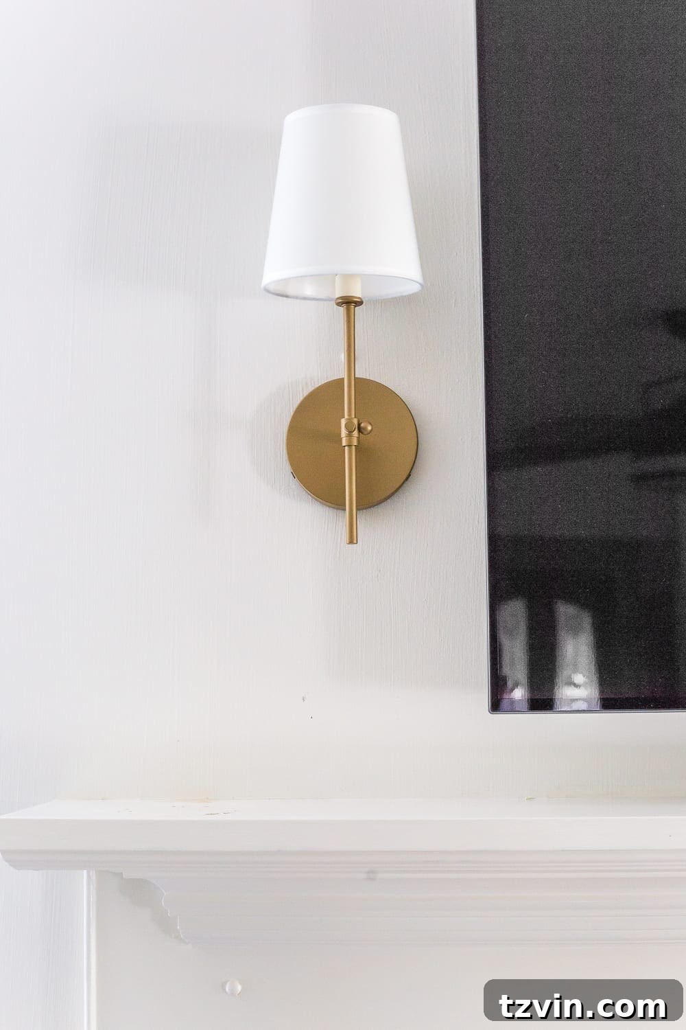 Beyond the Screen 12 Ways to Style Your TV Space 4 Detailed view of updated minimalist mantel with brass-finish sconces and fireplace screen