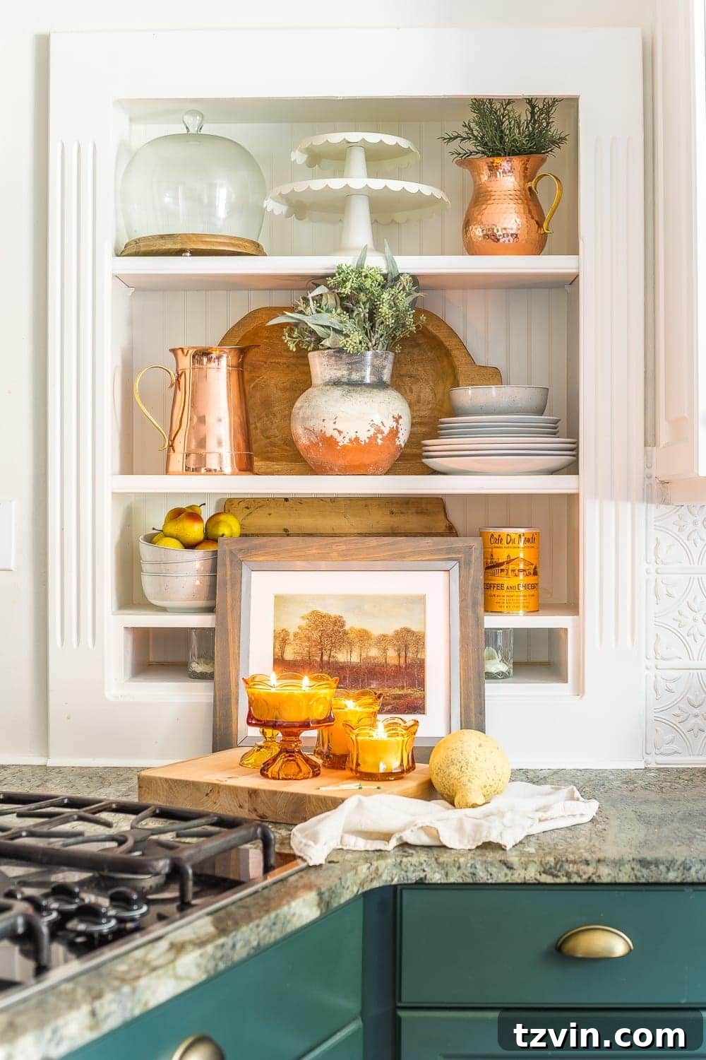 Styled kitchen shelves featuring DIY amber glass candles, copper pitchers, and faux greenery, creating a cozy fall decor display