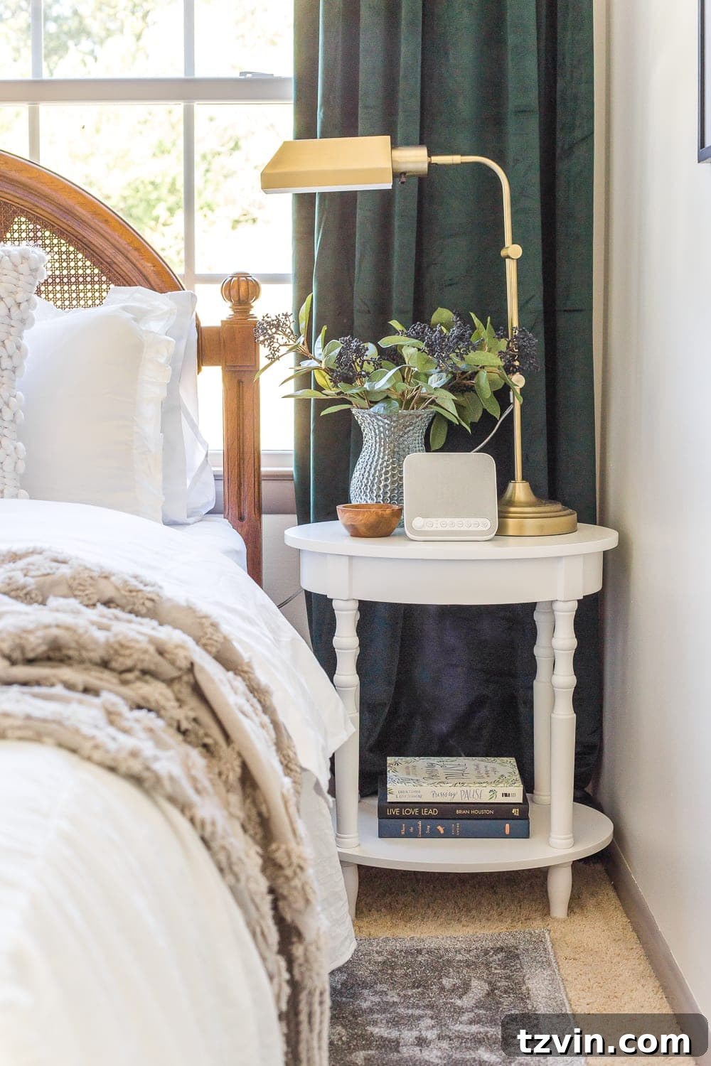 A bedside table with a lamp and books, illustrating the importance of good lighting and reading material in a welcoming guest bedroom.