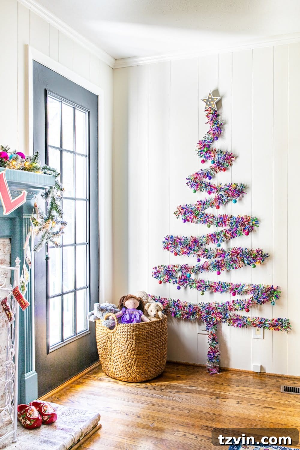 Finished DIY Christmas wall tree with colorful tinsel garland and lights in a playroom, styled for a vibrant holiday atmosphere.