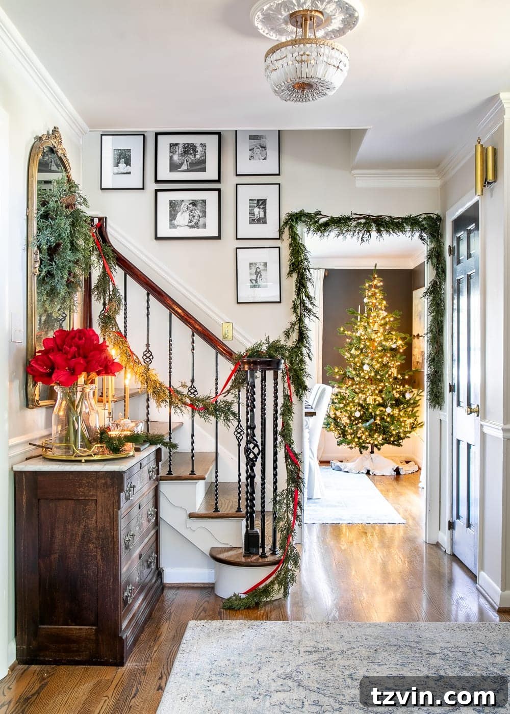 Modern meets traditional Christmas foyer with red amaryllis and realistic faux garland