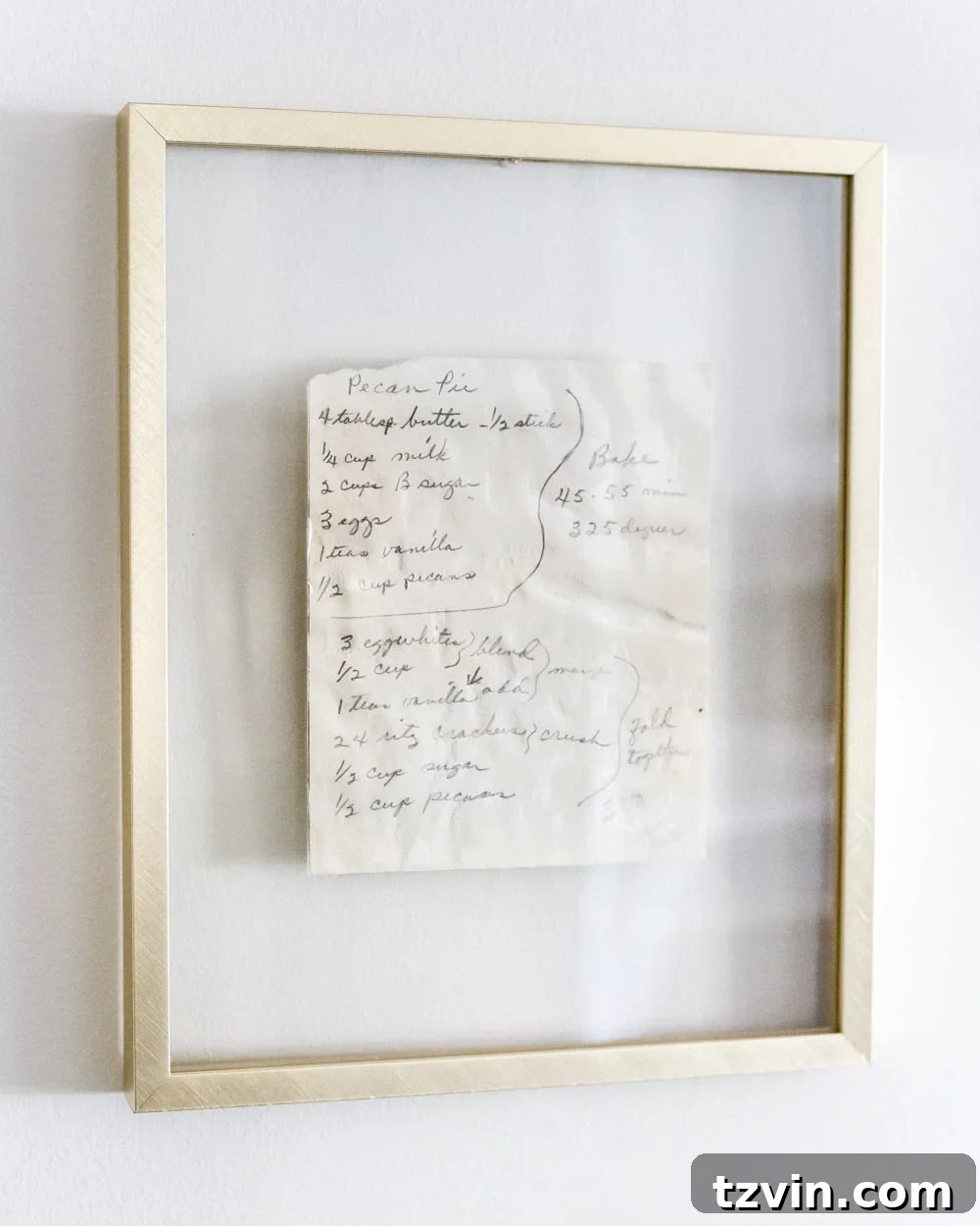 Handwritten family recipes displayed in brass float frames in a kitchen