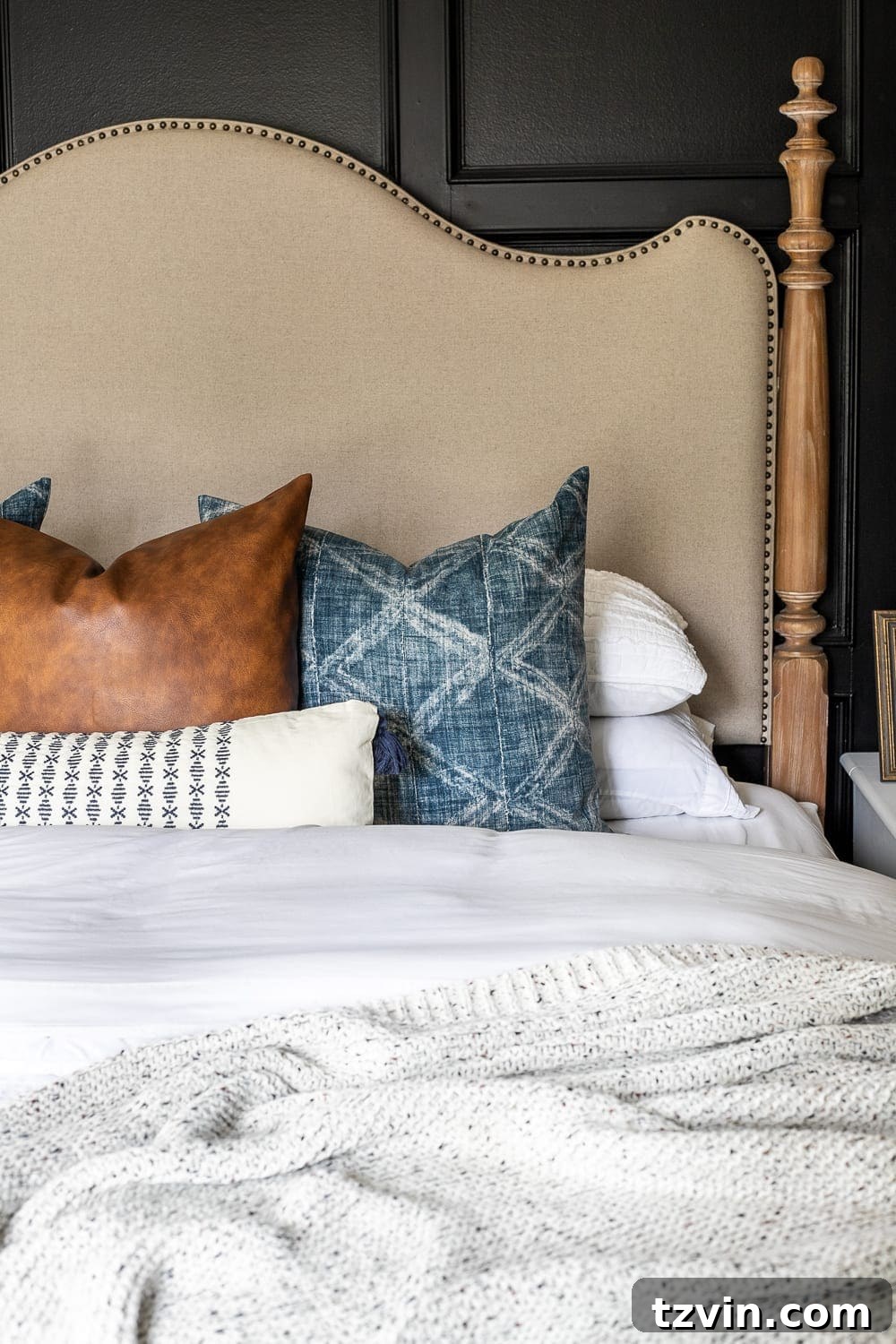 Moody Modern Vintage Master Bedroom Transformation 6 Modern vintage master bedroom featuring black walls, a traditional bed with light bedding, mud cloth and faux leather throw pillows, and warm wood nightstands.