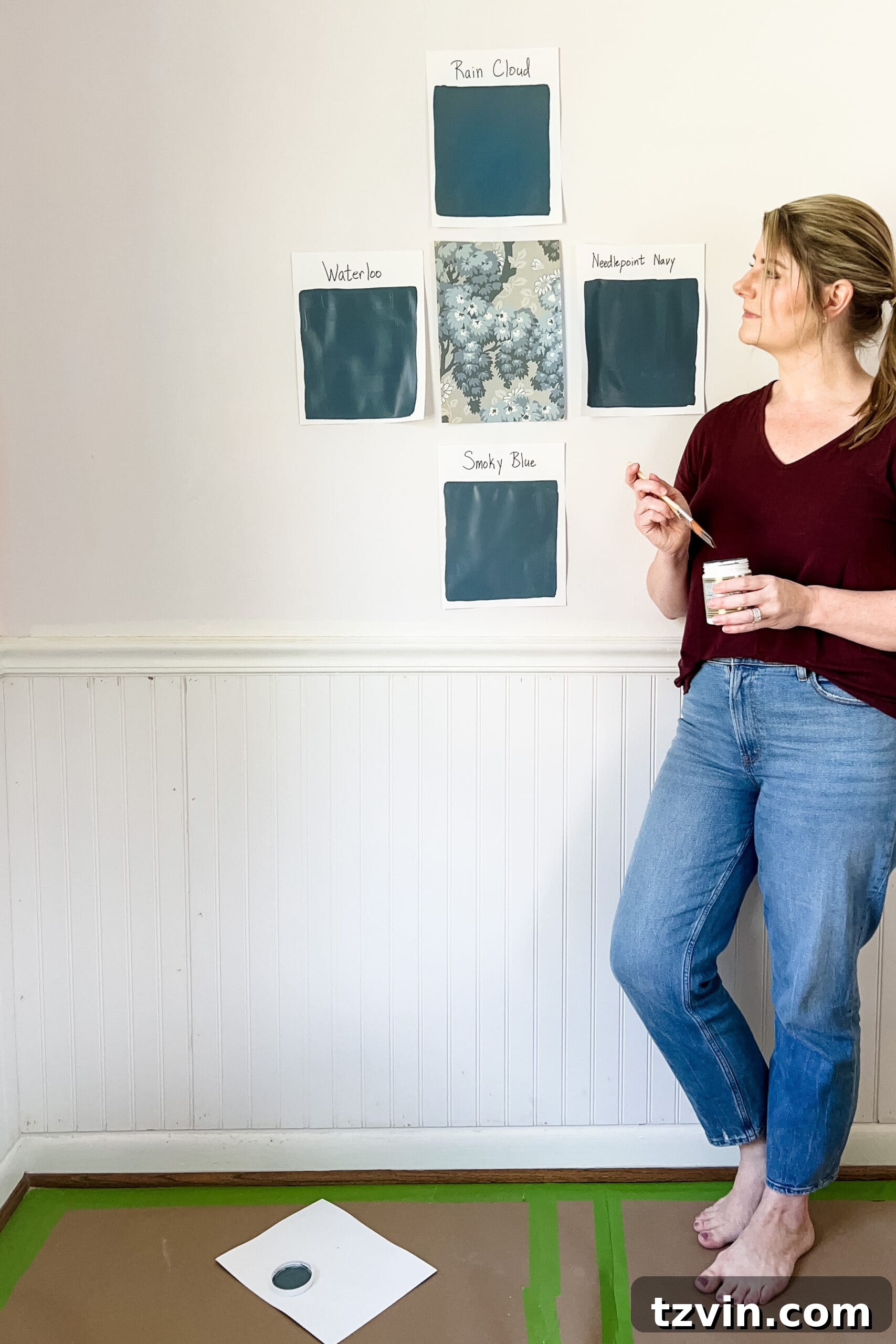 Paint color samples on white card stock testing various blue shades like Sherwin Williams Needlepoint Navy, Rain Cloud, Waterloo, and Smoky Blue for a bedroom, demonstrating the best way to choose paint colors for your home interior.