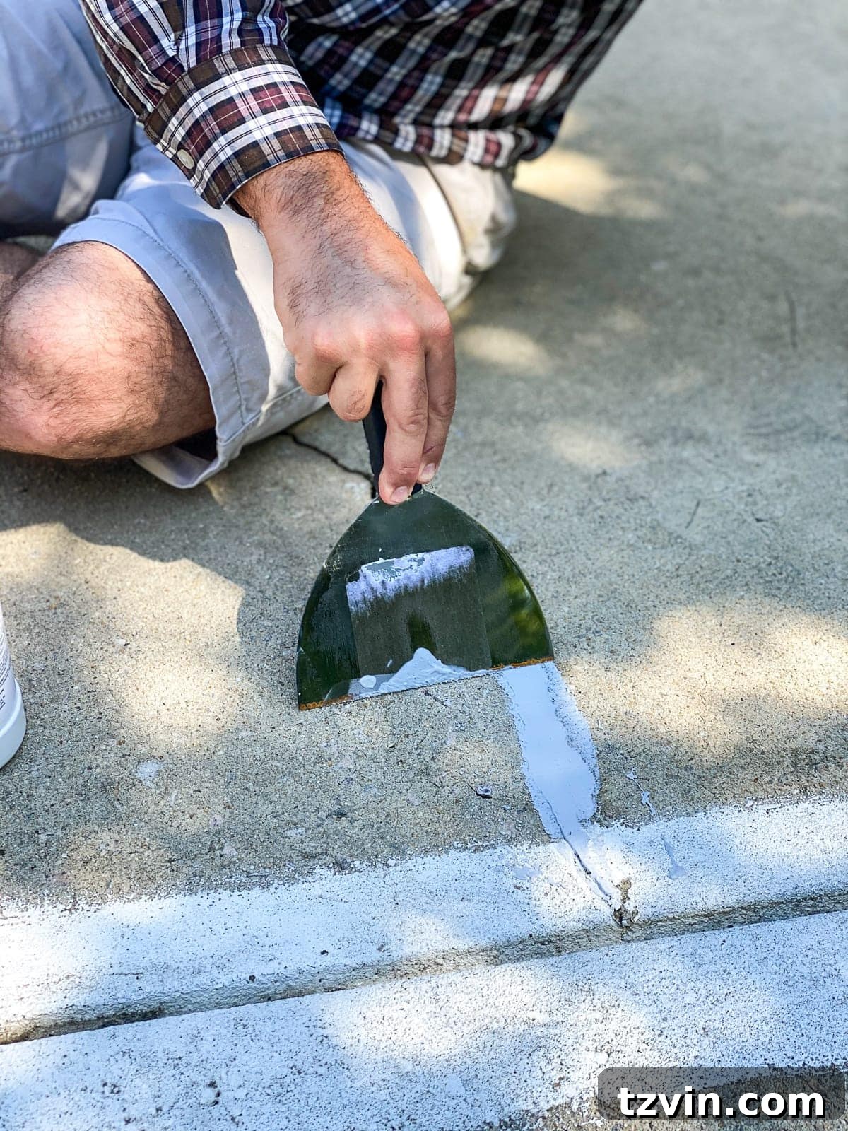 spreading concrete filler to patch cracks and holes