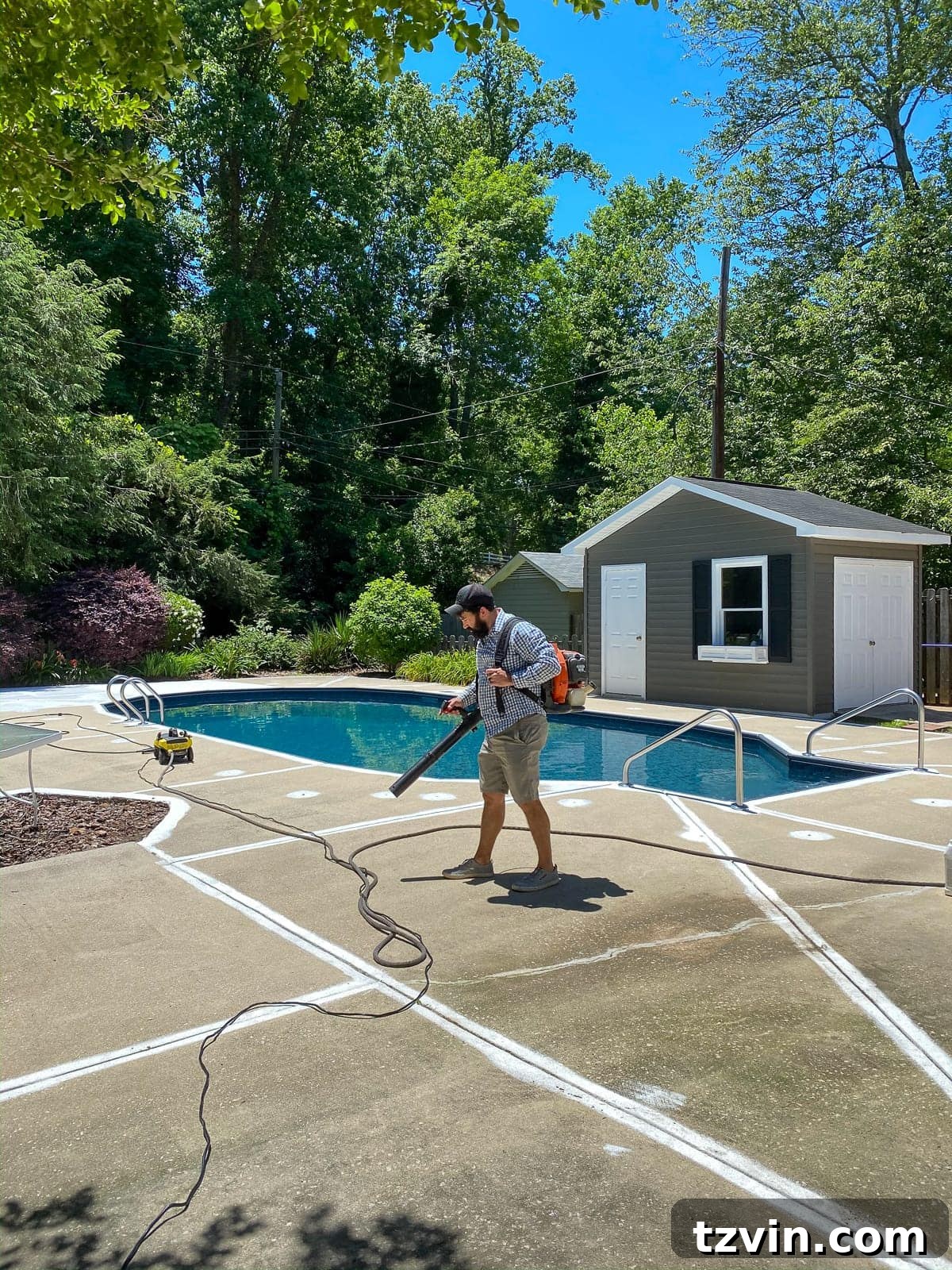 prepping a pool deck for painting by blowing off debris