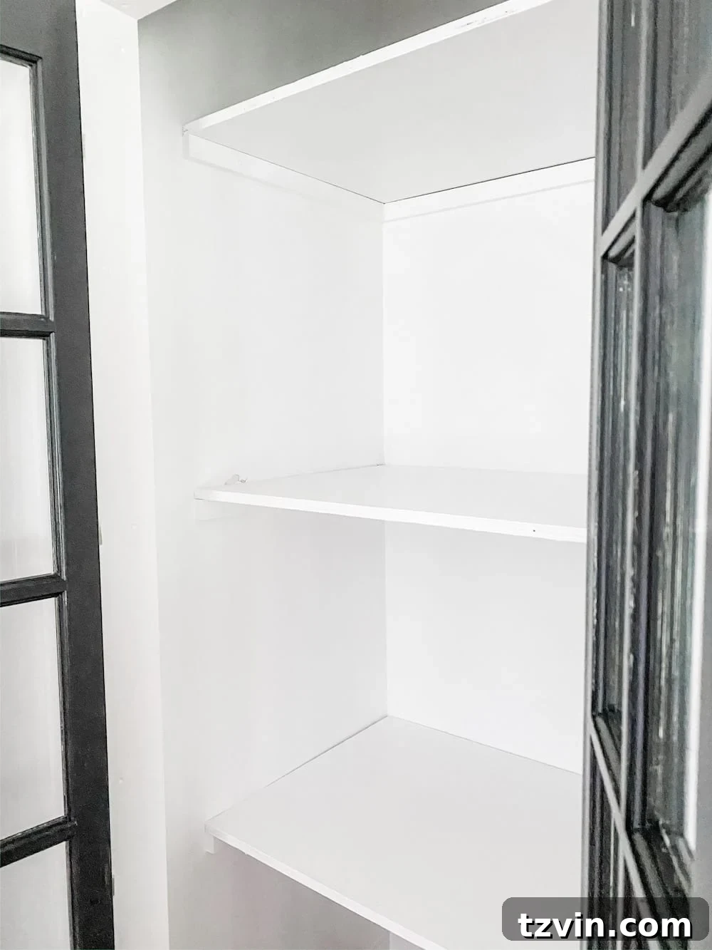 Simple Closet Transformation: Shelves and French Doors 12 Newly installed and painted white wooden shelves inside a closet, ready for organization.