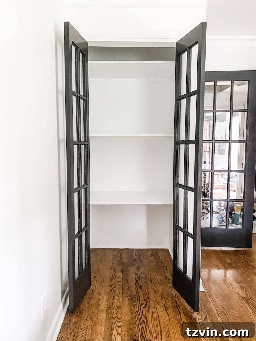 Simple Closet Transformation: Shelves and French Doors 13 French doors painted in a dark, rich color, with freshly installed white shelves visible through the glass panes.