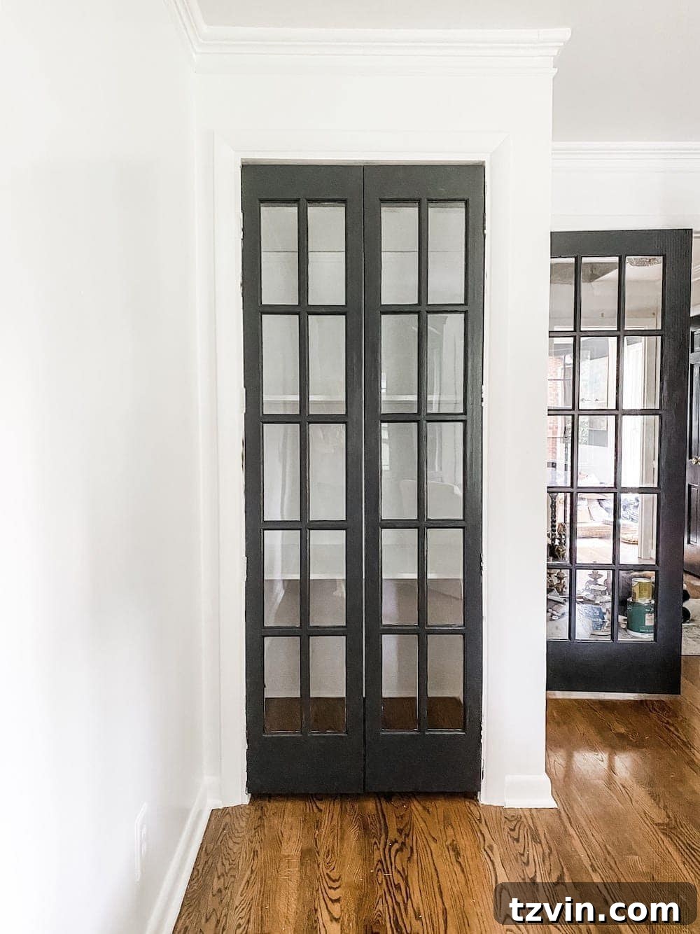 Simple Closet Transformation: Shelves and French Doors 14 Open French closet doors revealing newly painted white shelves inside, bathed in natural light, ready for home office organization.