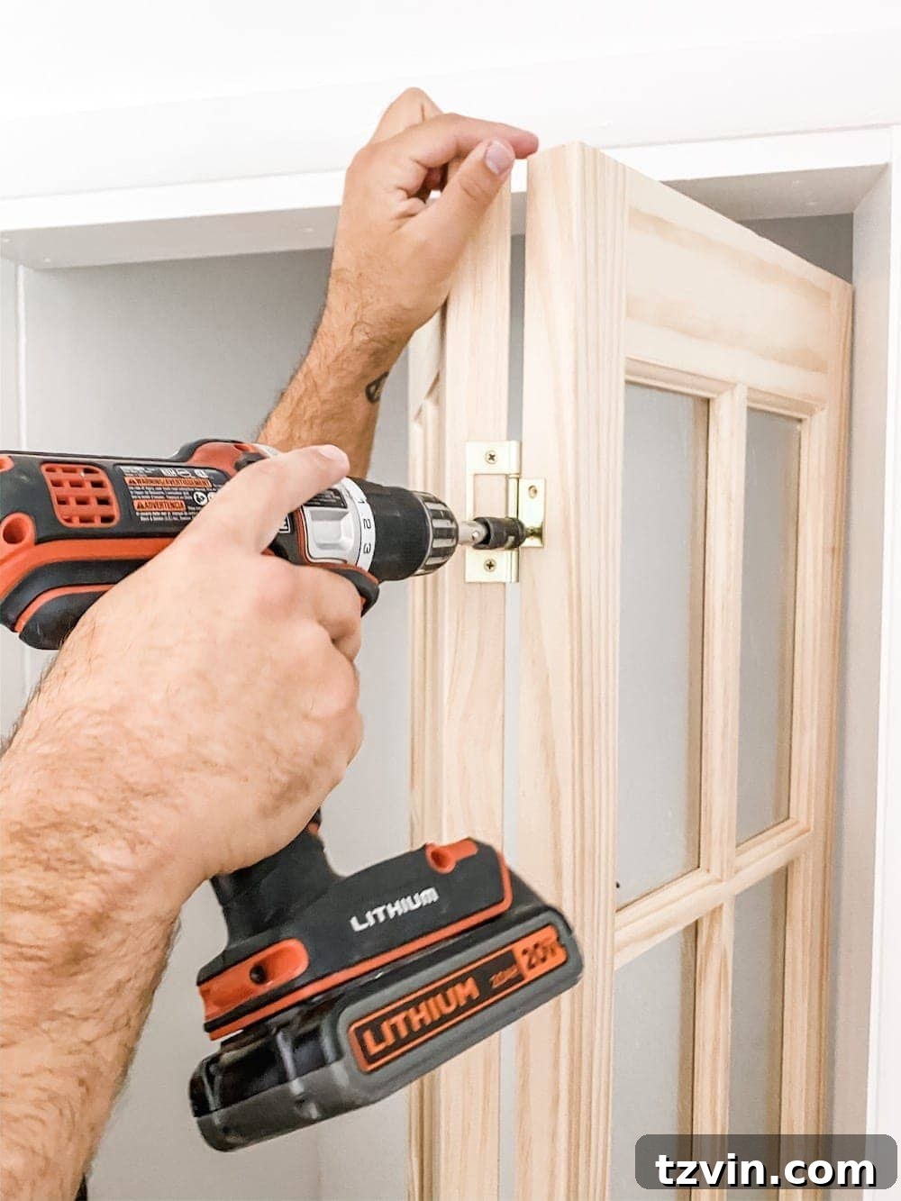 Simple Closet Transformation: Shelves and French Doors 4 Close-up of a hand unscrewing hinges from a bi-fold door panel, illustrating the first step of converting it into a French door.