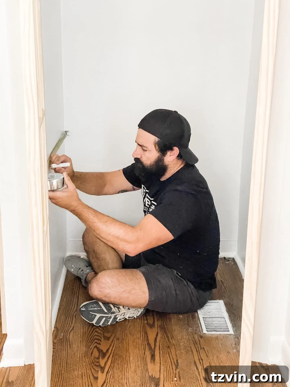 Simple Closet Transformation: Shelves and French Doors 7 A person measuring and marking shelf placement on a white closet wall with a pencil and tape measure.