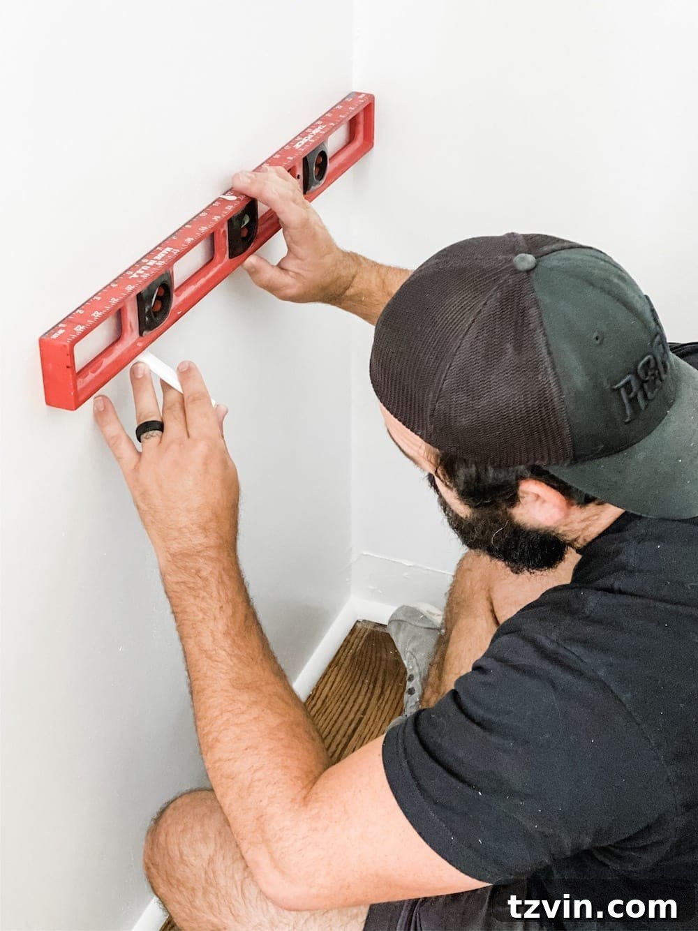 Simple Closet Transformation: Shelves and French Doors 8 A person using a level and stud finder to mark a horizontal line and stud locations on a closet wall for shelf installation.