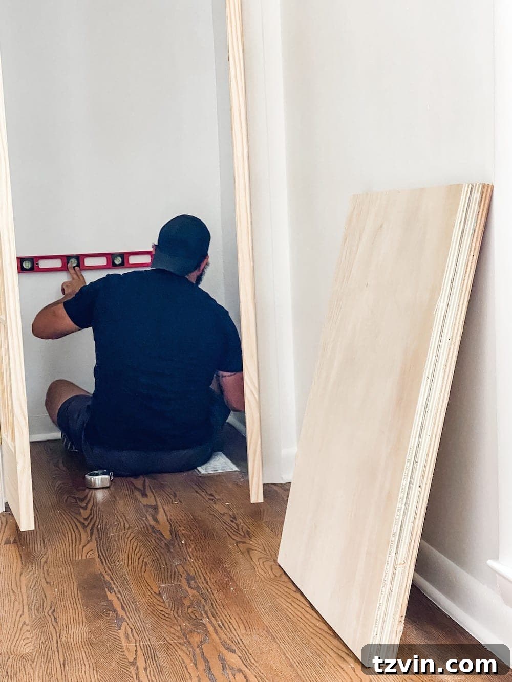 Simple Closet Transformation: Shelves and French Doors 9 A person using a circular saw to cut a large sheet of plywood for custom closet shelves.