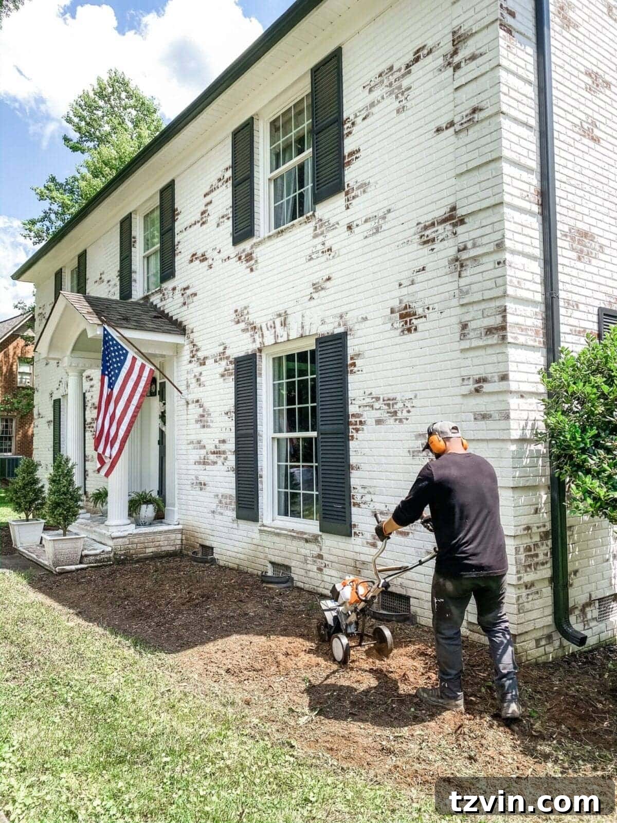 DIY Front Yard Flower Bed Glow Up 12 Person operating a tiller to break up compact soil in a flower bed