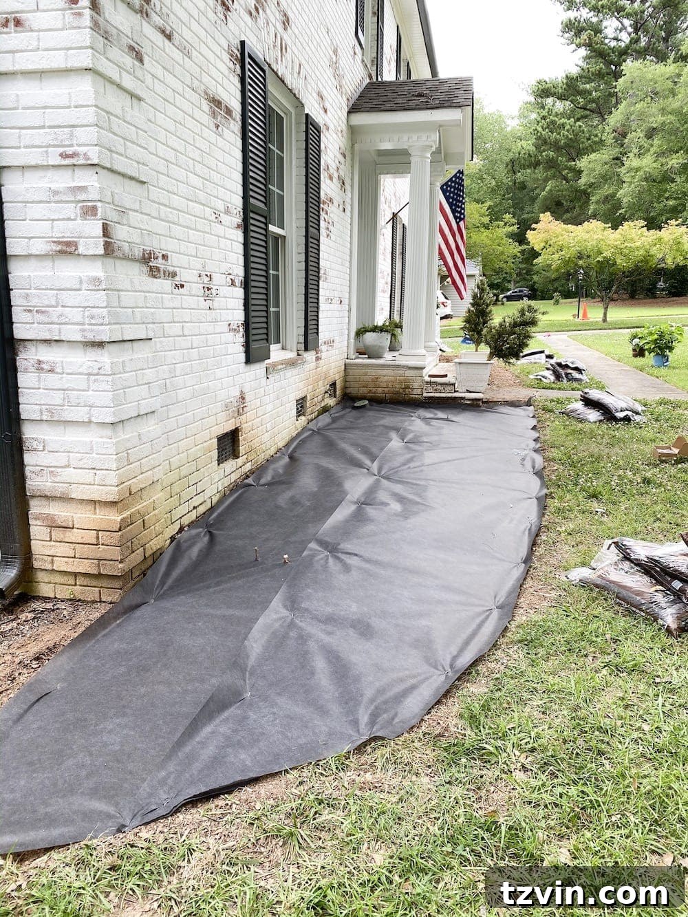 DIY Front Yard Flower Bed Glow Up 13 Laying black landscape fabric over tilled soil in a newly edged flower bed