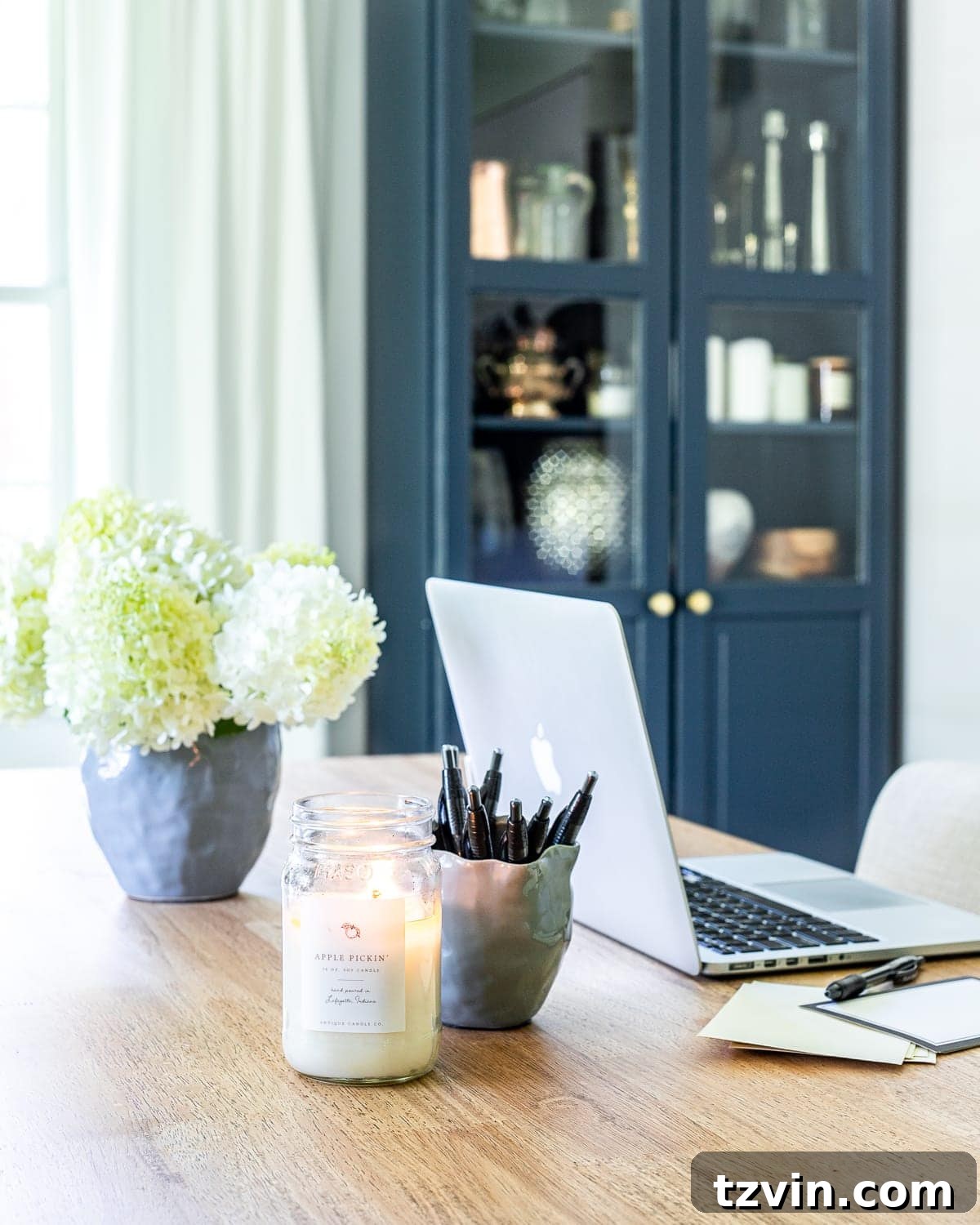 Our Home Office Transformation Unveiled 7 Home office decor featuring a large customized work table, upholstered rolling chairs, and a pendant light, creating an inviting workspace.