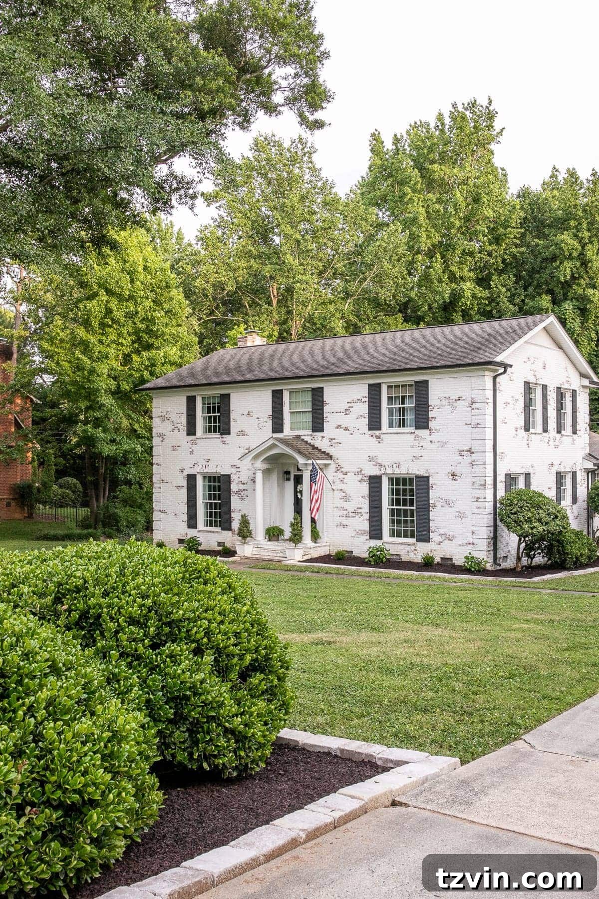 Stunning exterior view of a transformed home with refreshed landscaping and dark shutters.