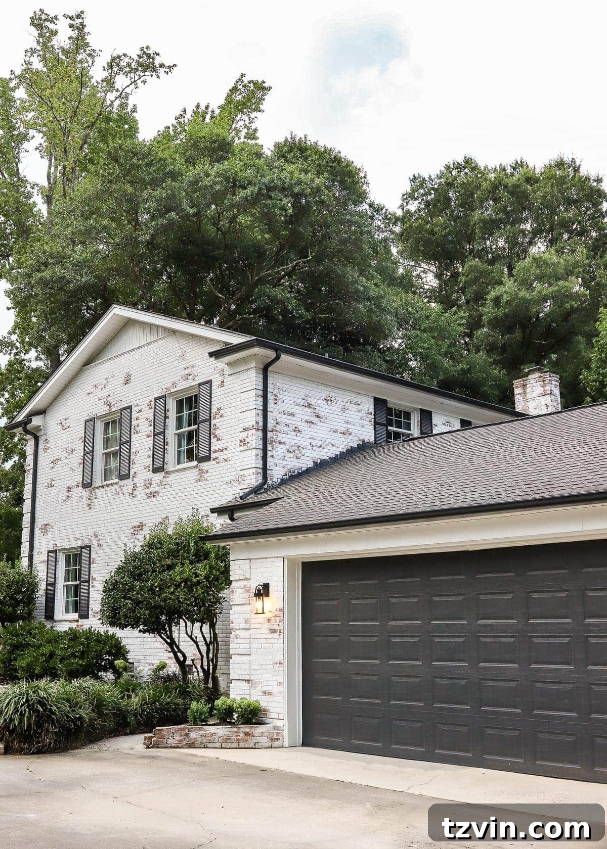 Close-up of freshly mulched flower beds with stone edging against a limewashed brick house.