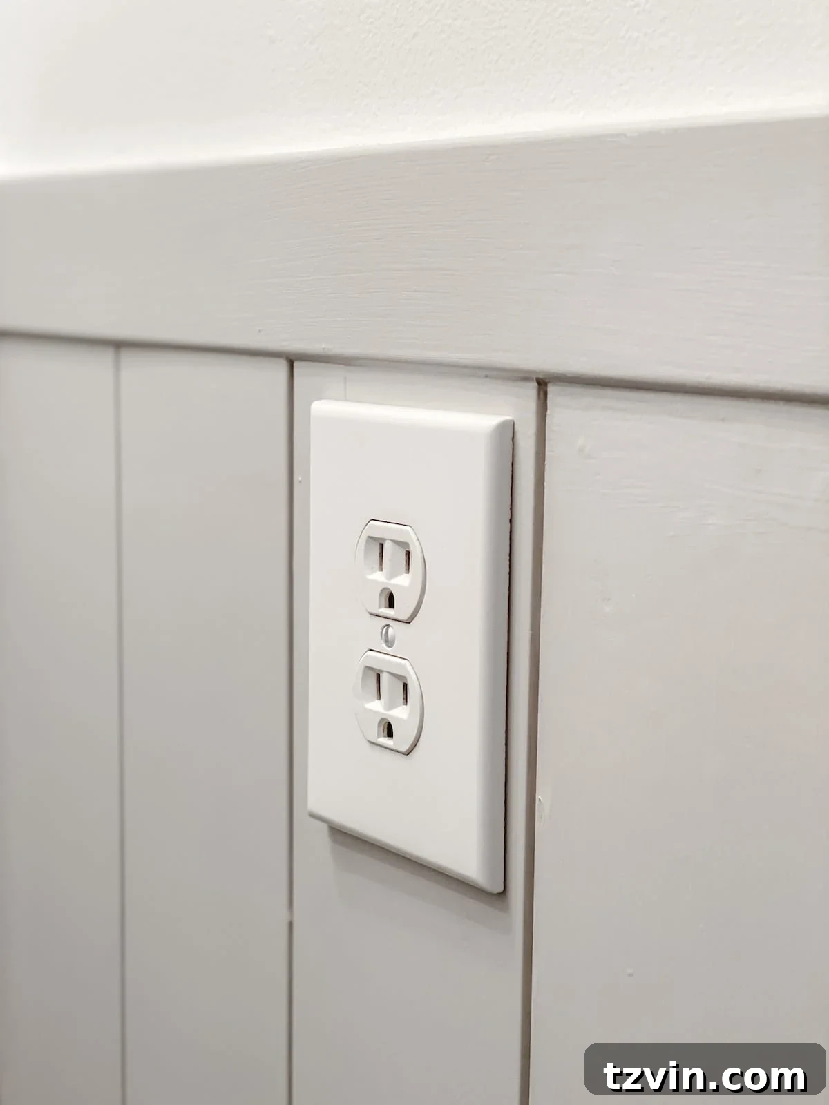 A newly installed oversized outlet cover on vertical shiplap wainscoting, showcasing a clean and finished look in a modern bathroom.
