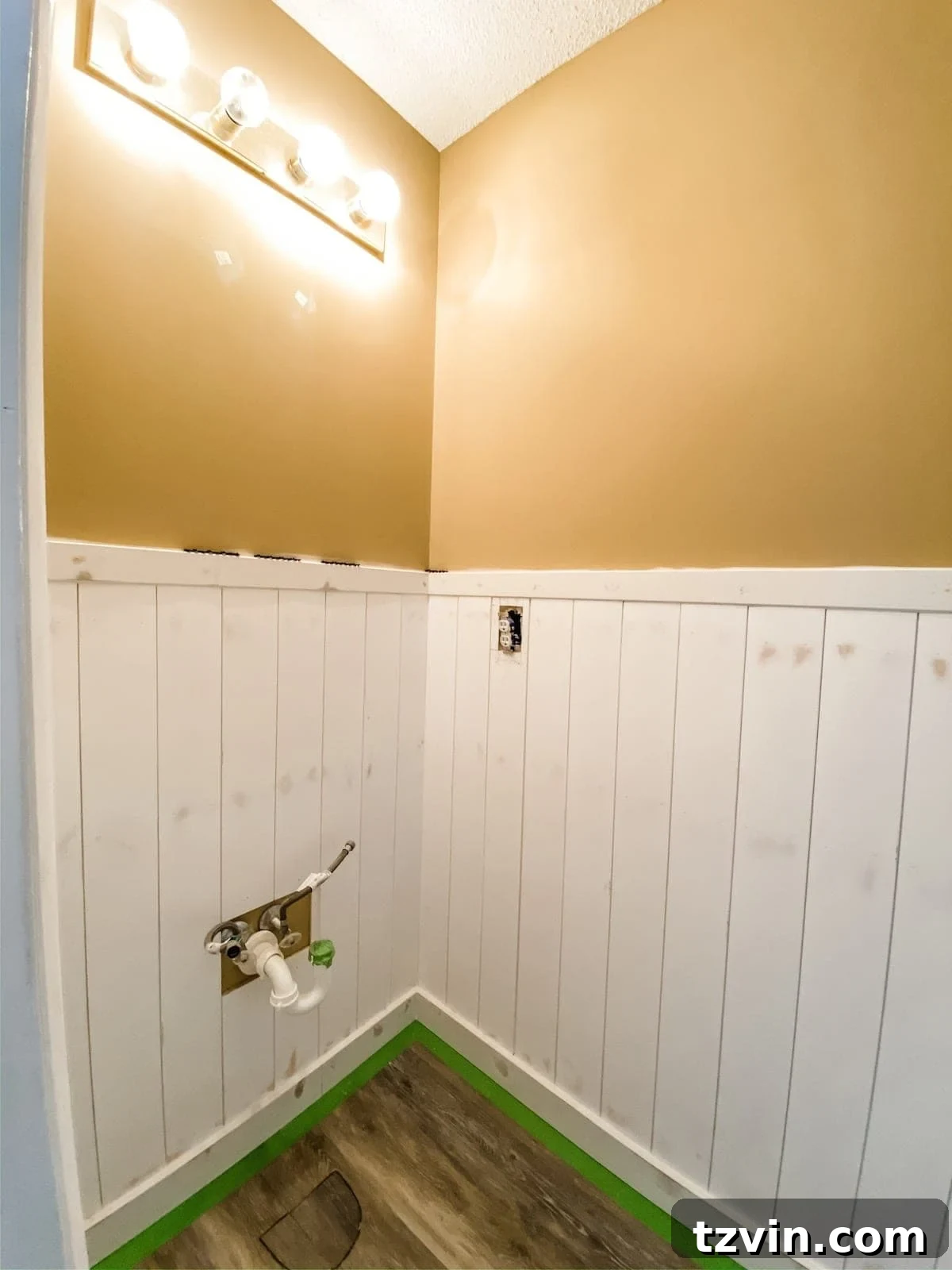 Vertical shiplap wainscoting installed in a bathroom, showing the pre-painted, smooth finish with filled nail holes and caulked seams, ready for the final coat of paint.