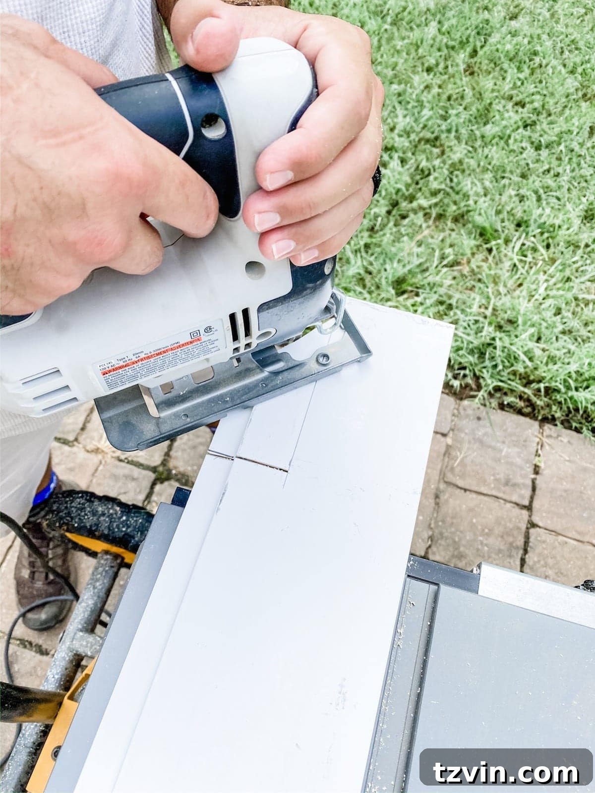 A person skillfully uses a jigsaw to cut out an opening for an electrical outlet from a shiplap board, demonstrating careful craftsmanship for a flush fit.