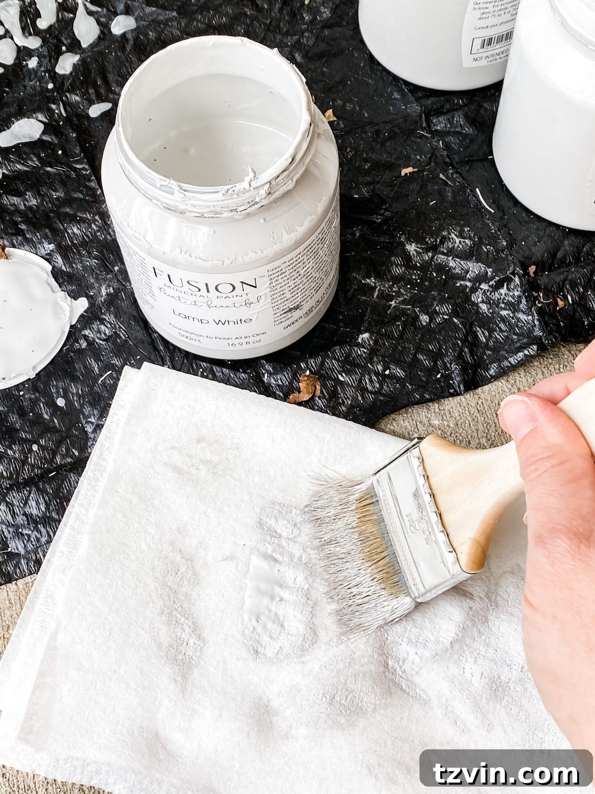 Demonstration of dry brushing technique with white paint on the gray lamp base, creating texture.