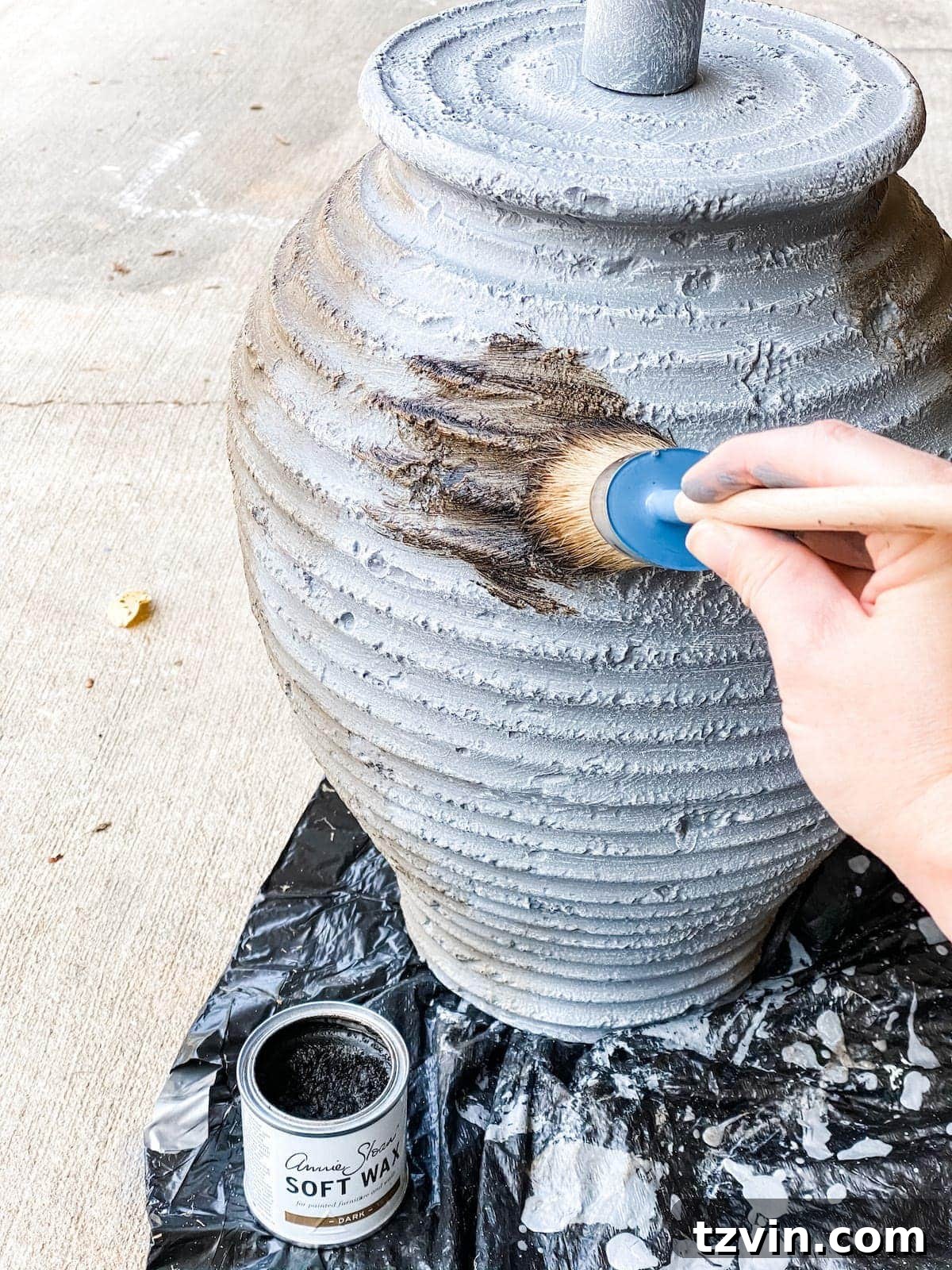 Applying dark wax finish to the gray painted lamp, enhancing texture and adding an aged patina.