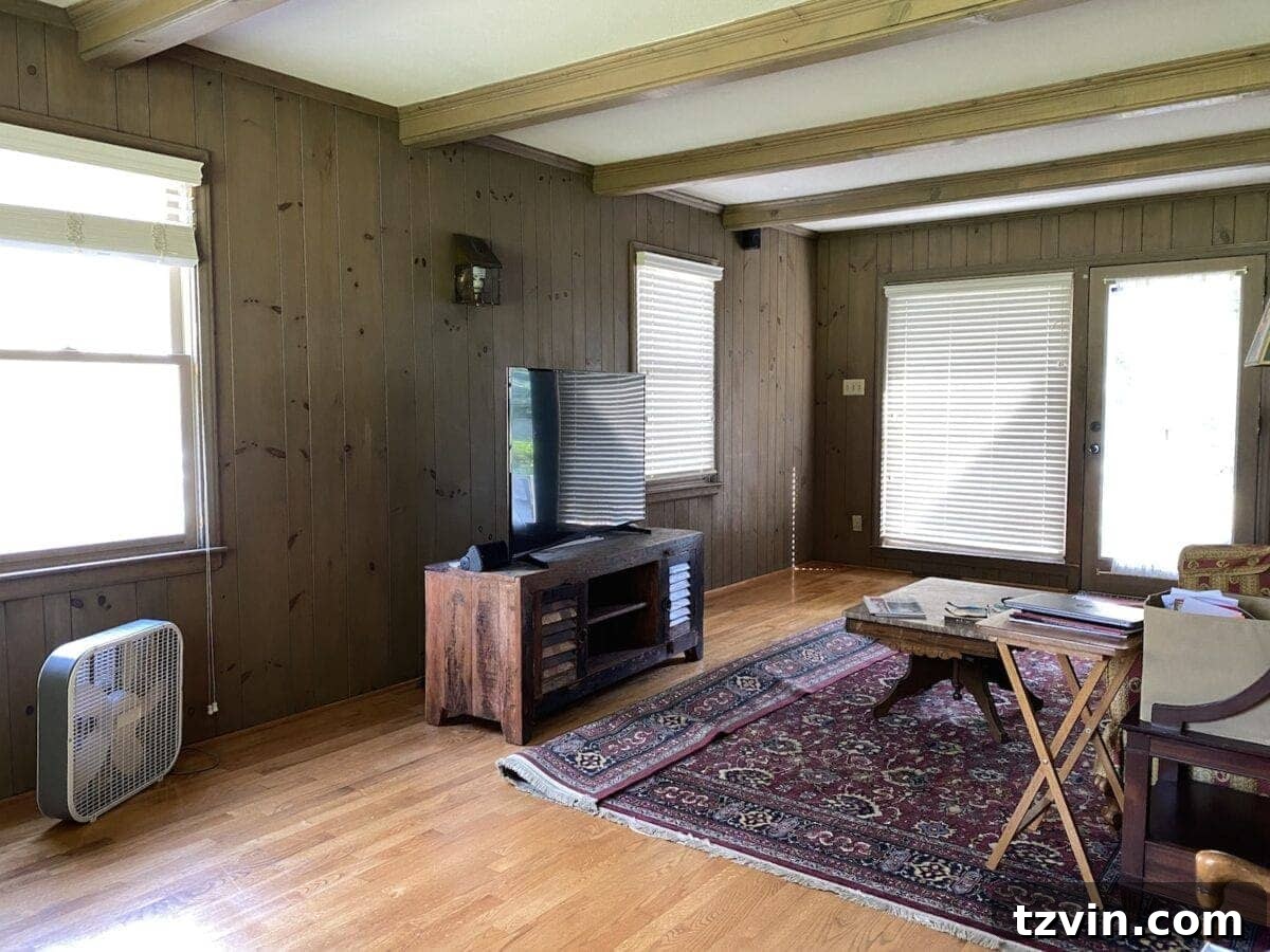 McNay Project Modern Coastal Living Room Tour 2 Before: A traditional living room with natural wood beams, planked walls, and large windows.