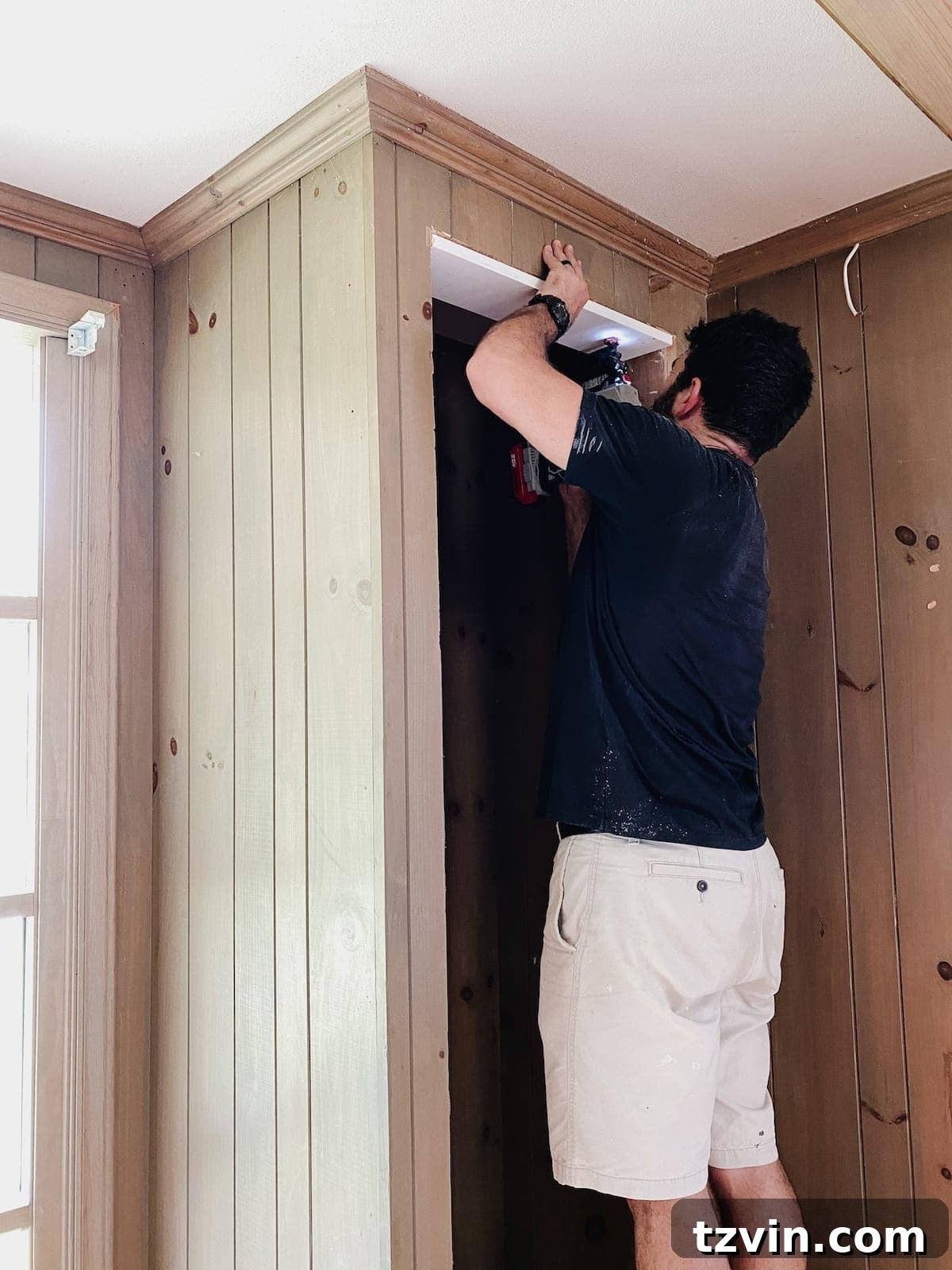 Worker installing a 1x6 board as part of the new header for built-in shelves