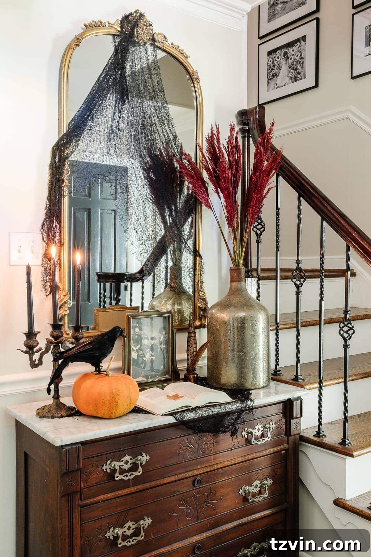 A tastefully decorated entryway with vintage Halloween art prints, pumpkins, and fall foliage, creating an inviting yet spooky atmosphere.